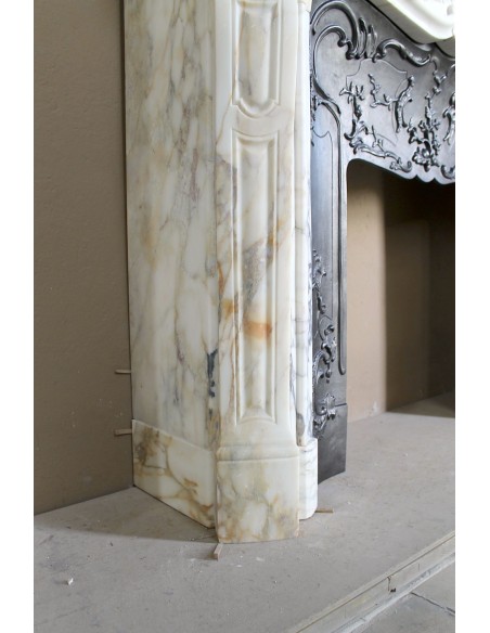 An antique refined Louis XV “Coquille” fireplace mantel in Calacatta Gold marble with its original floral cast-iron insert.