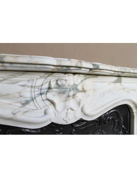 An antique refined Louis XV “Coquille” fireplace mantel in Calacatta Gold marble with its original floral cast-iron insert.