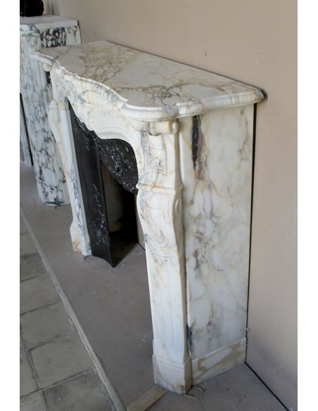 An antique refined Louis XV “Coquille” fireplace mantel in Calacatta Gold marble with its original floral cast-iron insert.