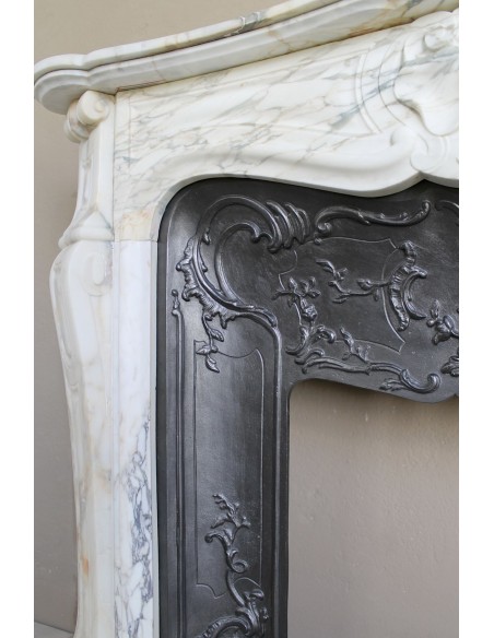 An antique refined Louis XV “Coquille” fireplace mantel in Calacatta Gold marble with its original floral cast-iron insert.