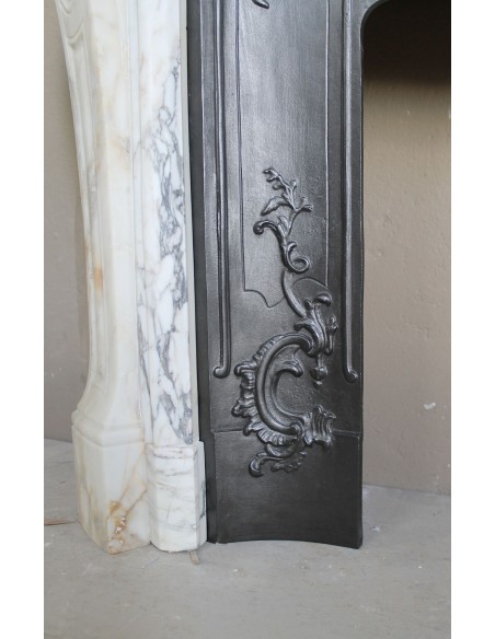An antique refined Louis XV “Coquille” fireplace mantel in Calacatta Gold marble with its original floral cast-iron insert.