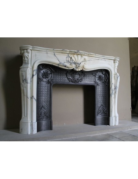 Important antique Louis XV “Coquille Bordelaise” fireplace mantel in rare Pavonazzo marble, with its original cast-iron insert.