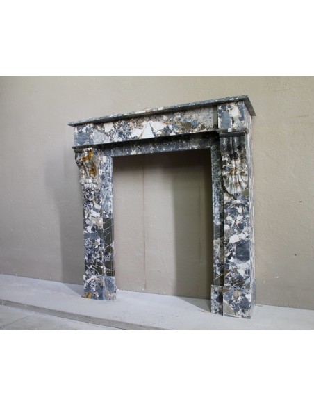 Antique “Palmettes” fireplace in a charmingly compact size, carved in Black marble with richly varied multicoloured veining.