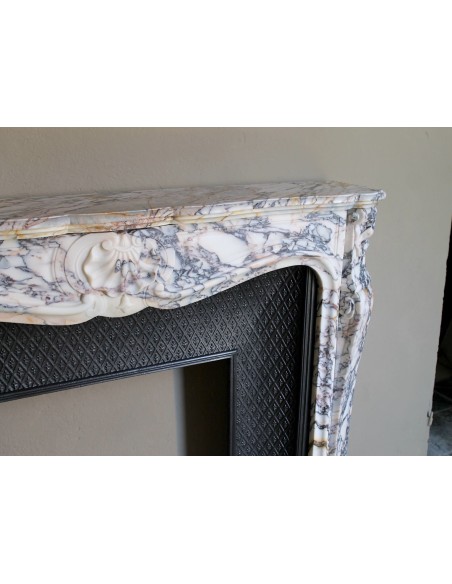 Antique Louis XV fireplace in Calacatta Gold marble with striking gold, violet and pink veining, with original cast-iron insert.