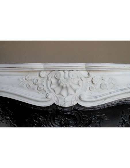 Impressive Baroque antique fireplace in Statuary White marble, featuring elegant floral carvings, and a cast-iron insert.