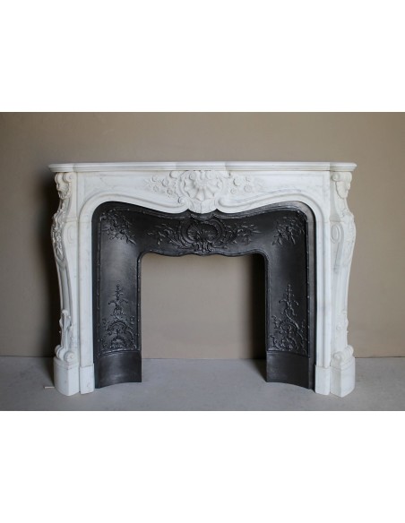 Impressive Baroque antique fireplace in Statuary White marble, featuring elegant floral carvings, and a cast-iron insert.