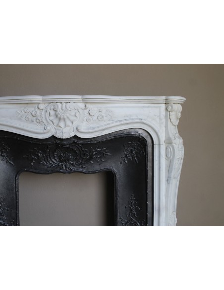 Impressive Baroque antique fireplace in Statuary White marble, featuring elegant floral carvings, and a cast-iron insert.
