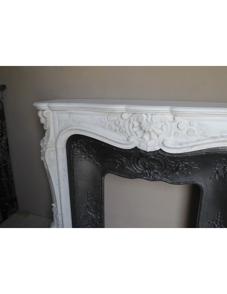 Impressive Baroque antique fireplace in Statuary White marble, featuring elegant floral carvings, and a cast-iron insert.