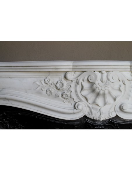 Impressive Baroque antique fireplace in Statuary White marble, featuring elegant floral carvings, and a cast-iron insert.