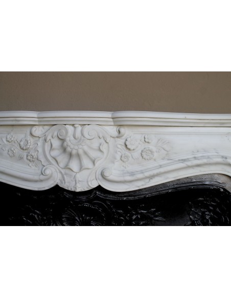 Impressive Baroque antique fireplace in Statuary White marble, featuring elegant floral carvings, and a cast-iron insert.