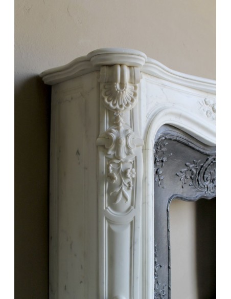 Impressive Baroque antique fireplace in Statuary White marble, featuring elegant floral carvings, and a cast-iron insert.