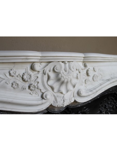 Impressive Baroque antique fireplace in Statuary White marble, featuring elegant floral carvings, and a cast-iron insert.