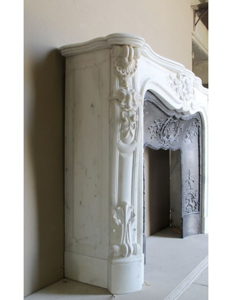 Impressive Baroque antique fireplace in Statuary White marble, featuring elegant floral carvings, and a cast-iron insert.