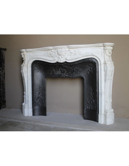 Impressive Baroque antique fireplace in Statuary White marble, featuring elegant floral carvings, and a cast-iron insert.