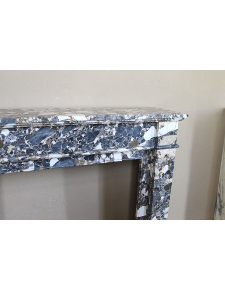 Antique Neoclassical marble fireplace, with minimalist lines and elegant multicolored veining on a dark background.