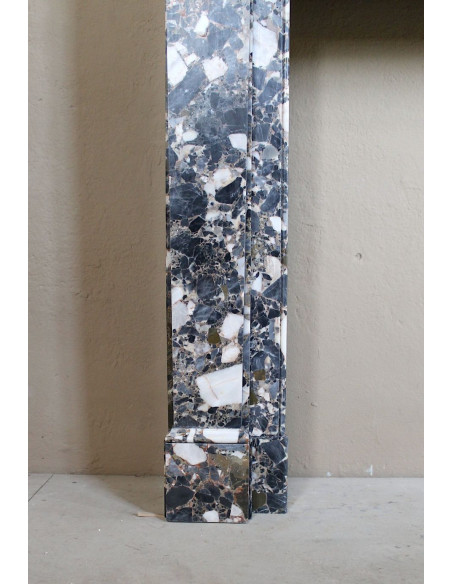 Antique Neoclassical marble fireplace mantel, with minimalist lines and elegant multicolored veining on a dark background.