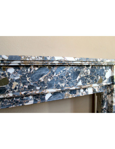 Antique Neoclassical marble fireplace mantel, with minimalist lines and elegant multicolored veining on a dark background.