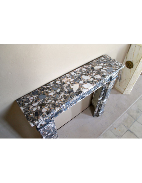 Antique Neoclassical marble fireplace mantel, with minimalist lines and elegant multicolored veining on a dark background.