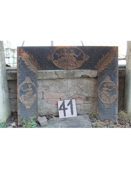 Antique cast iron insert with putti decorations and elegant background with floral tapisserie.