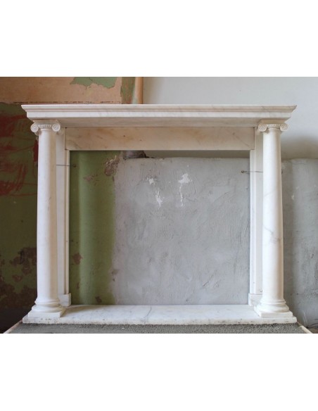 Antique fireplace mantel carved from solid Statuary marble. On either side are columns with Corinthian capitals.